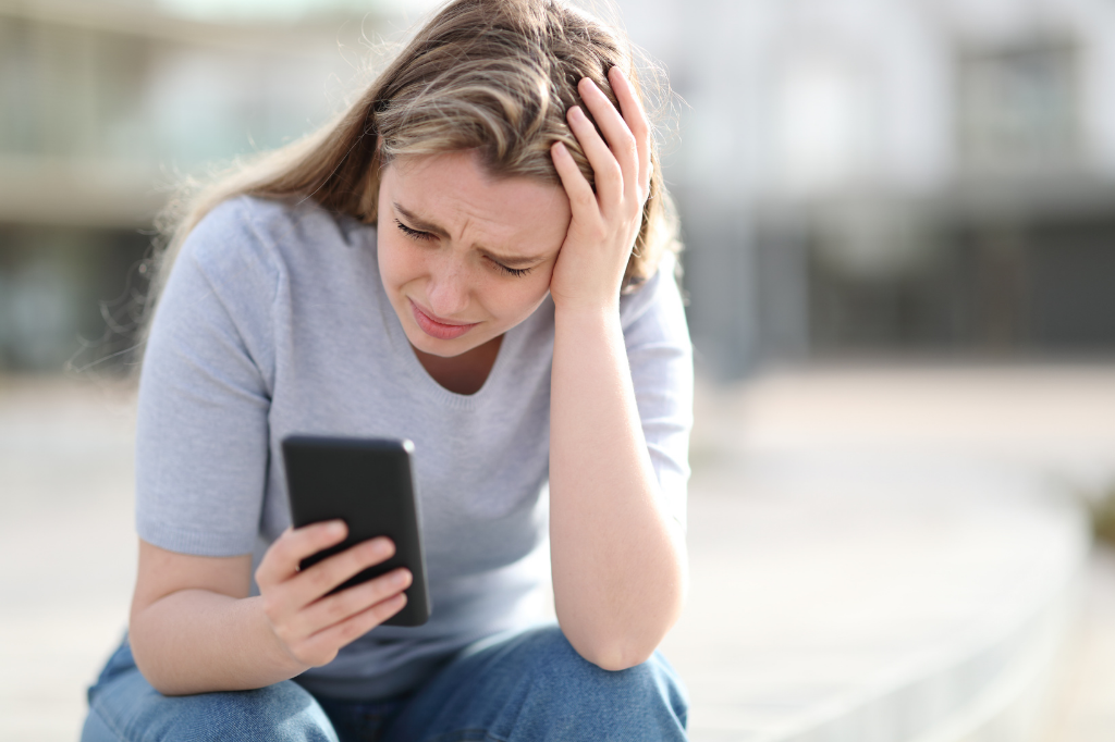 Sad teen girl reads tragic news on her cell phone.