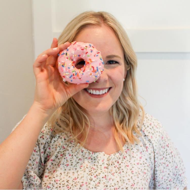 Laura Cragun, Intuitive Eating Coach, looks through a pink sprinkled donut