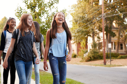 Tween and teen girls walk down a sunny street