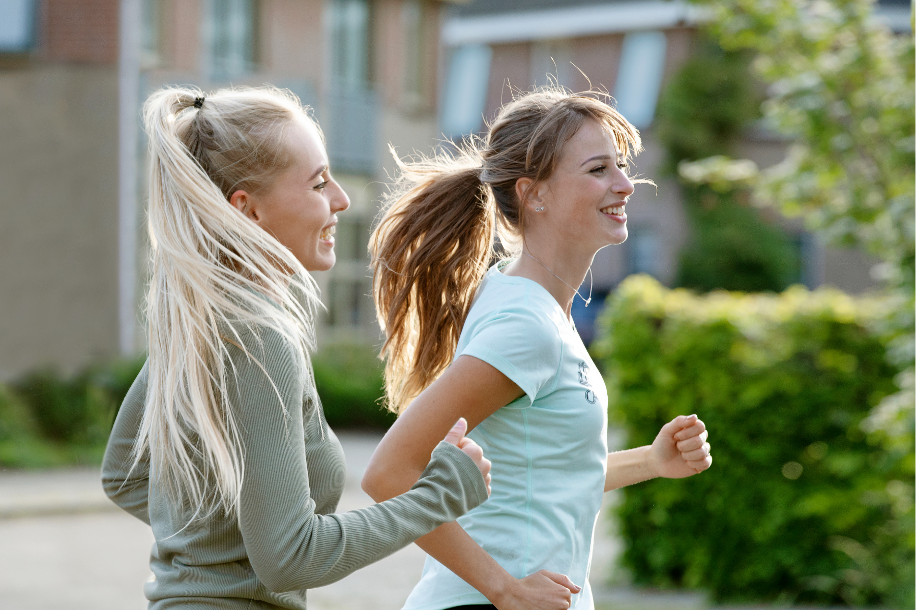 Tween and teen girls with long ponytails go for a jog on a sunny day