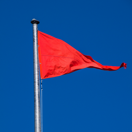 A red flag waves against a blue sky