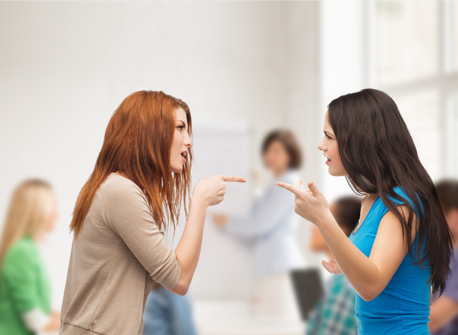Two teen or tween girls fight pointing at each other.