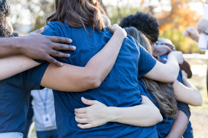 Teen and tween girl volunteers group together with their arms around each other as they make change happen.