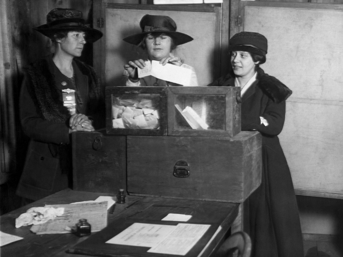 Women in history, a black and white photo from 1917 of three women's suffragists casting votes in New York City.