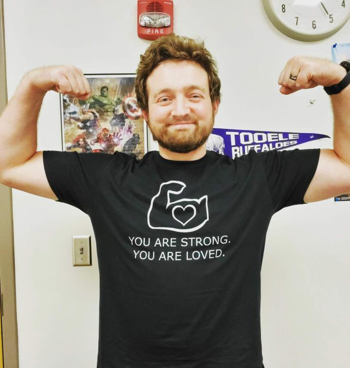 Nate Webb from @bulliesbe.gone flexes his arms while wearing a black shirt that reads "You are strong. You are loved."