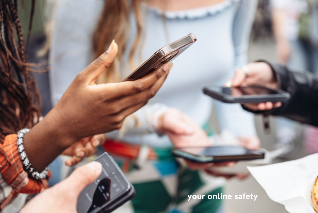 Teen and tween girls stand in a circle holding their smartphones.