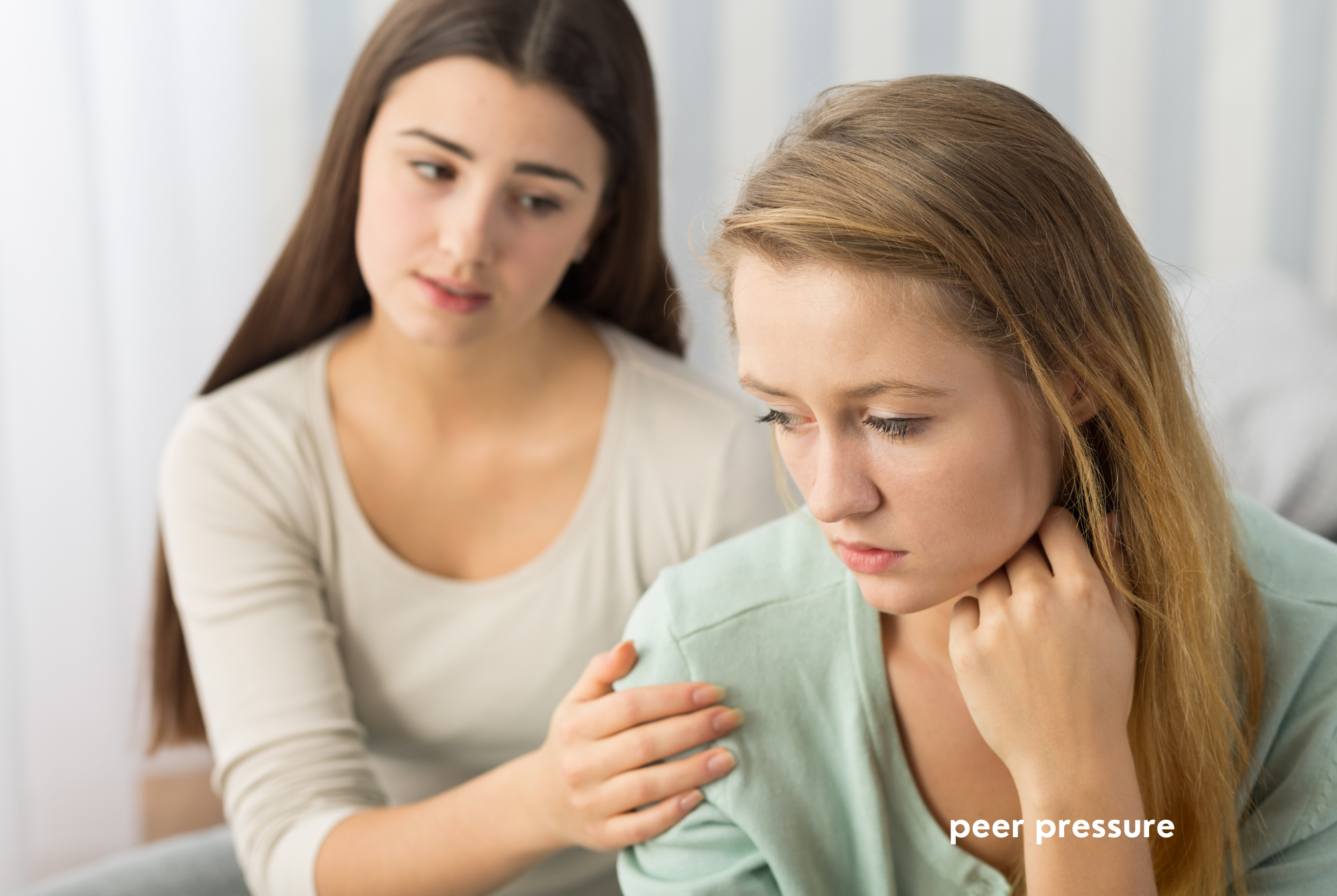 A tween or tween girl with long brown hair sits next to another teen or tween girl with long blonde hair and tries to peer pressure her.